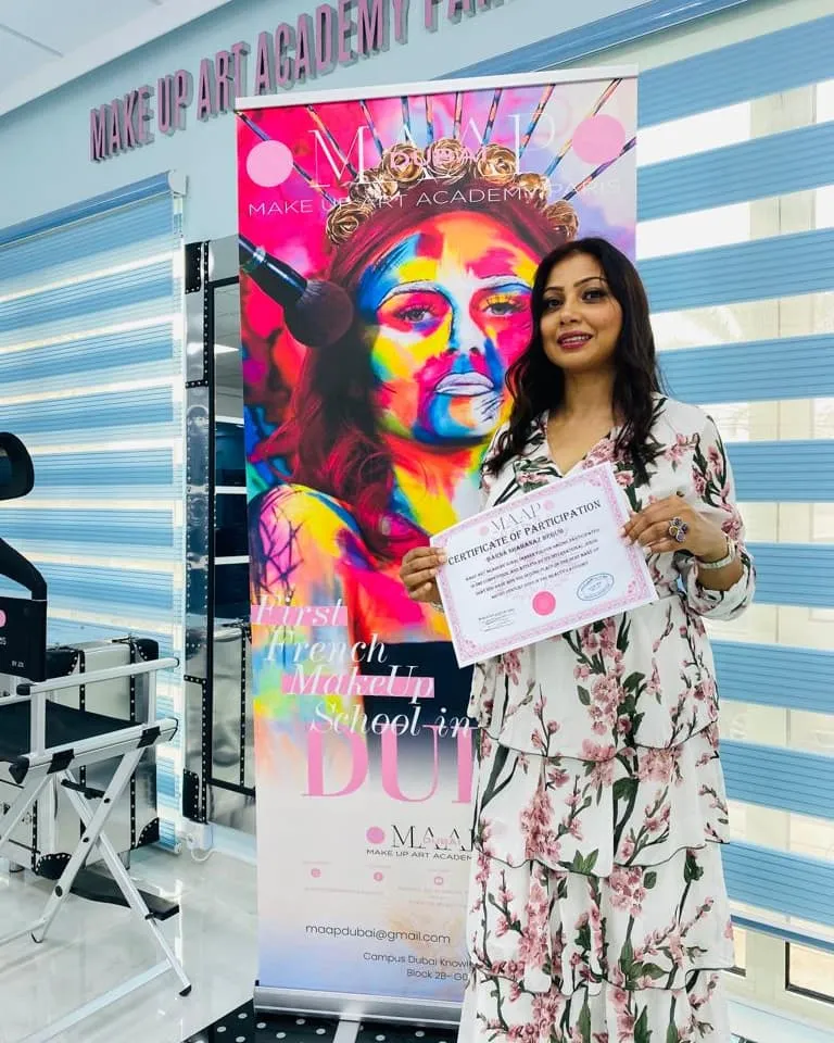Woman in a floral dress holding a certificate beside a colourful banner