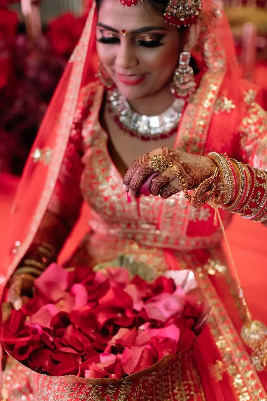 Bride in a red and white outfit with silver jewellery holding red rose petals