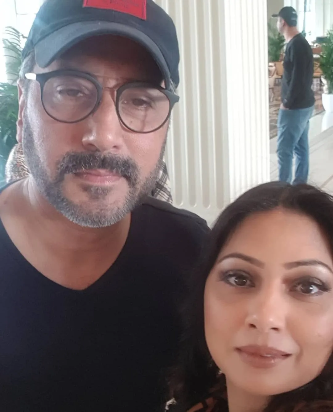 Selfie of a bearded man in a cap and glasses with a woman