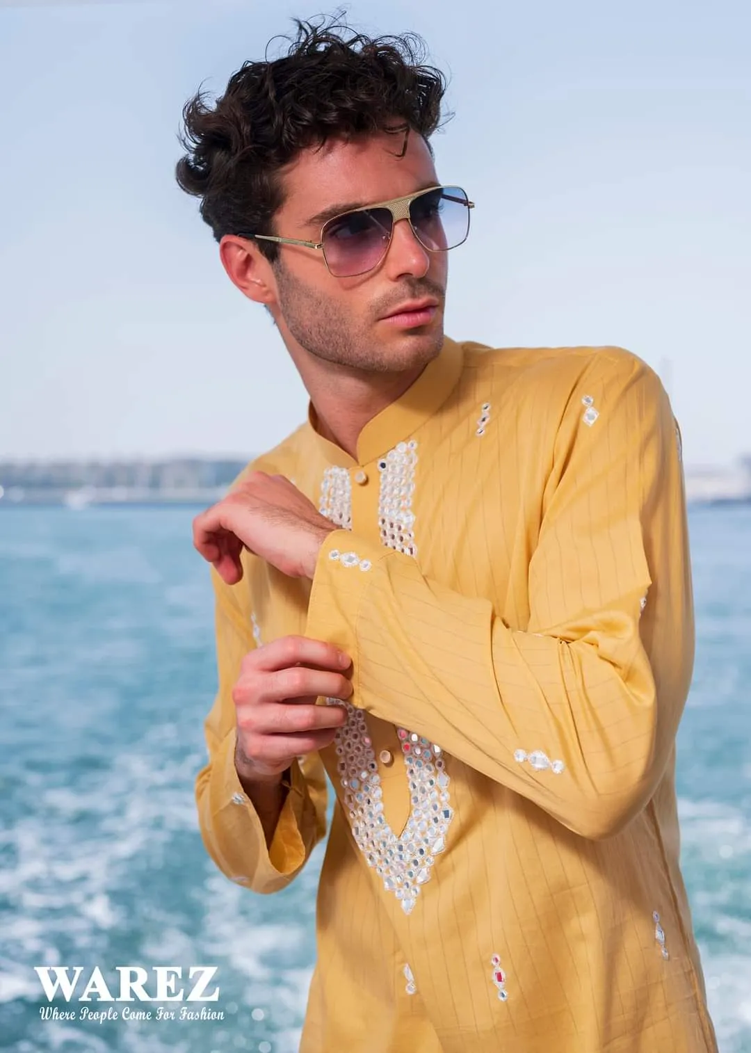 Man in sunglasses wearing a yellow embroidered kurta on a boat