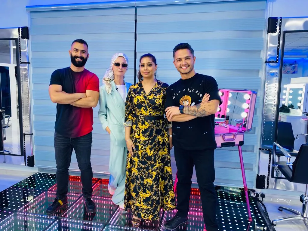 Four people posing together in a salon, two men in red and black t-shirts and two women