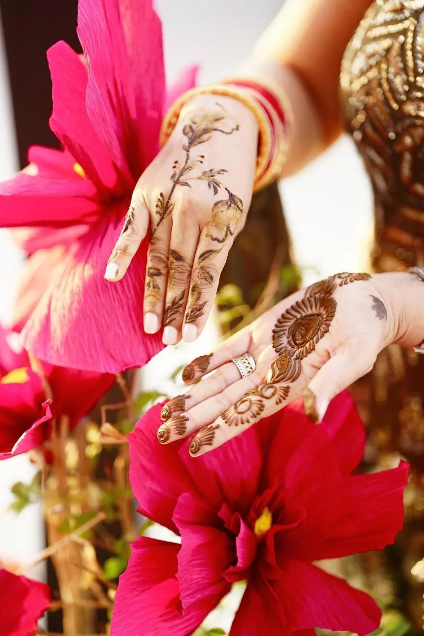 Bride in a pink silk saree with a gold border looking back over her shoulder, jasmine flowers in her bun