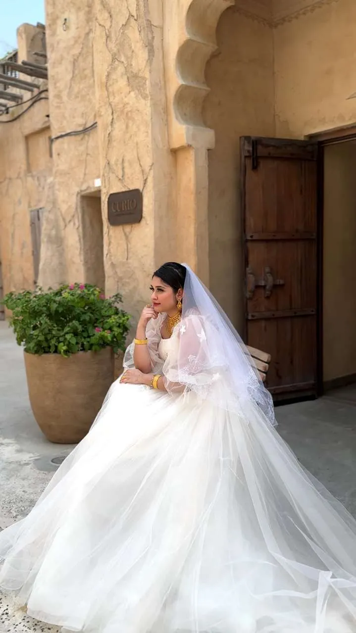 Bride in a white ball gown and veil standing in an arched sandstone doorway